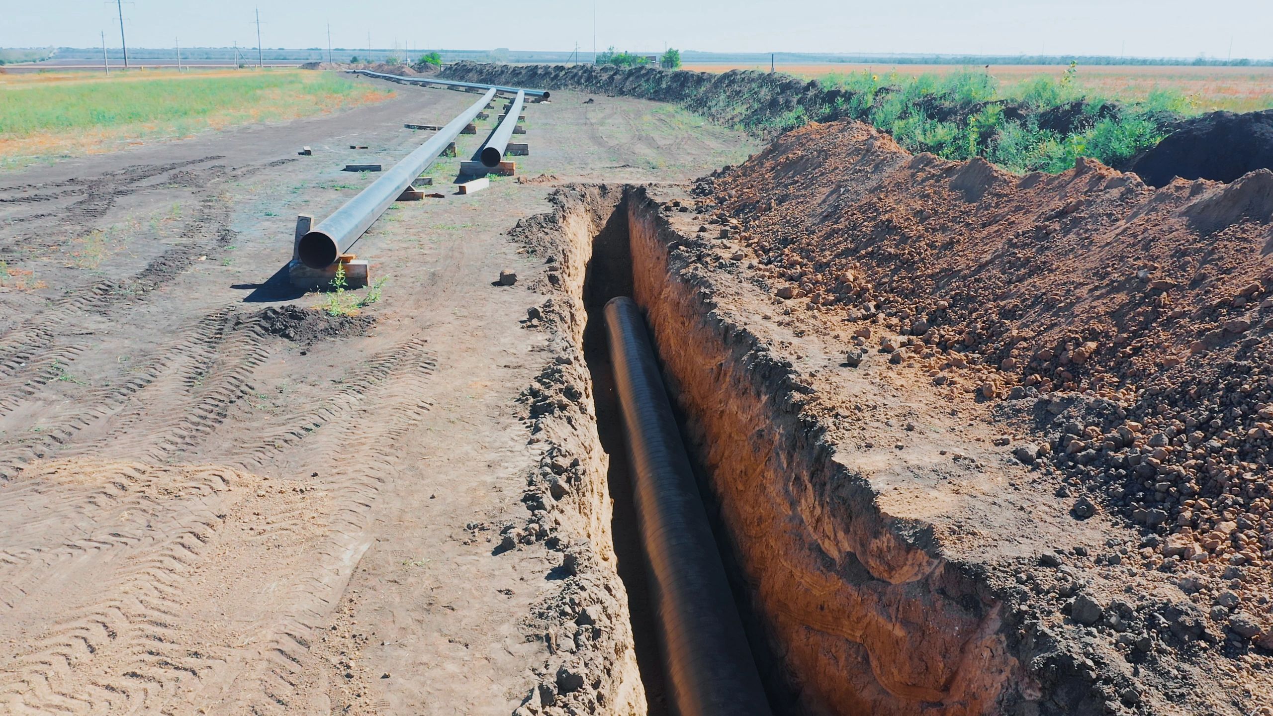 Pipeline construction trench with exposed utility pipe
