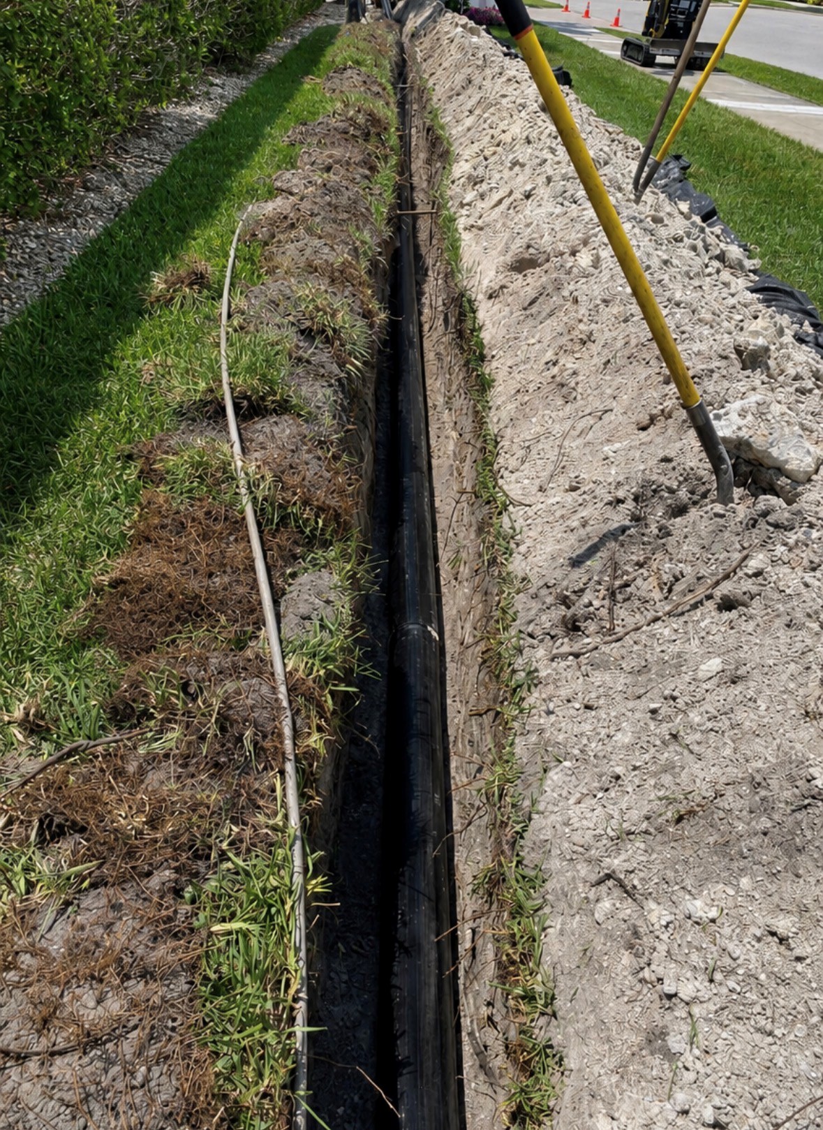 Water main replacement trench with installed pipe along roadside